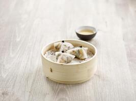 Steamed Black Truffle and Assorted Mushroom Dumpling served in a wooden bowl side view on grey marble background photo