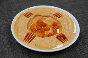 Spicy Hummus served in a dish isolated on wooden table background side view of appetizer photo
