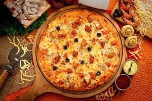 Seafood pizza with tomato sauce and mayo isolated on wooden board top view of italian food on wooden background photo