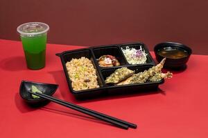 MIXED TEMPURA PREMIUM BENTO with mint margarita, sauce and chopsticks isolated on red background side view of japanese fast food photo