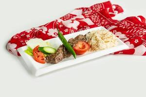 Turkish barbecues Sis lamb Kebab with rice and salad in a dish isolated on colorful table cloth top view on grey background photo