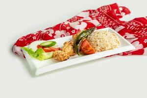 Turkish barbecues Sis Chicken Kebab with rice and salad in a dish isolated on colorful table cloth top view on grey background photo