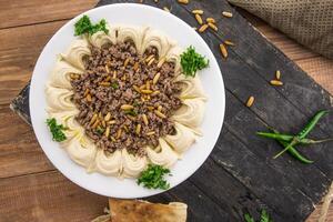 Beef hummus with pine nuts served in dish isolated on table side view of arabic food photo