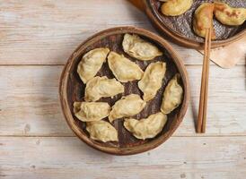 Handmade steamed dumplings and fried dumpling or momo served in wooden dish with chopsticks isolated on table top view Japanese food photo