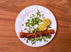 chicken kabab with lemon slice served in dish isolated on grey background top view of pakistani food photo