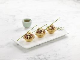 Wagyu Beef Tart served in a tray with chopsticks isolated on mat side view on grey marble background photo