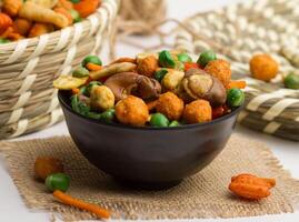 chinese mixed crackers served in a bowl isolated on napkin side view of nuts on grey background photo