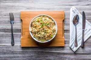 Hakka Noodles Vegetables with spoon and tissue isolated on wooden board top view on table fastfood photo