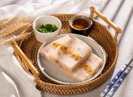 Delicious Chinese traditional turnip cake with spring onion, sauce and chopstick side view street food photo