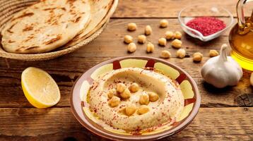 Hummus served in a dish isolated on wooden table background side view of appetizer photo