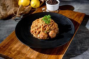 Classic Beef Bolognese pasta in a black dish with black pepper top view on dark background photo