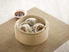 Steamed Dumpling with Preserved Olive Vegetable served in a wooden bowl isolated on mat side view on grey background photo