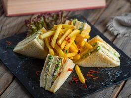 club sandwich with fries isolated on cutting board side view of fastfood on wooden background photo