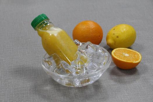 A bottle of healthy Orange and Lemon Juice with Basil Seeds served in iced cube bowl side view on grey background photo