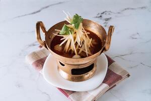 Chiang Pork Shoulder Curry in a copper stew dish isolated on mat top view on grey marble background photo