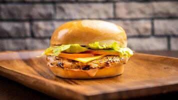 Chicken burger with cheese salad, tomato and leaf isolated on wooden board side view on table fast food photo