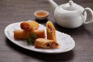 Crispy Vegetable Spring Roll with sauce served in a dish side view on dark background photo