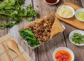 Dried Pork meat bento include Pig feet, rice, braised pork, with chilli sauce, noodles, bread, toast, spoon and chopsticks served in dish isolated on napkin top view of hong kong food photo