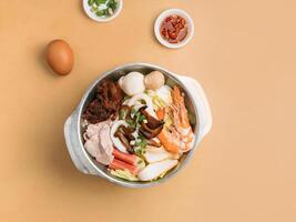 Tom Yum Xiao Wan in a bowl with soup, chili sauce and spring onion top view on wooden table photo