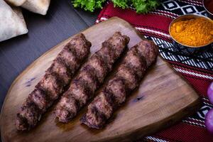 Spicy meat seekh Kebab served in wooden board isolated on table top view of arabic food photo