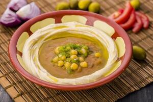 Hummus on it ful or fol with chickpeas served in dish isolated on table side view of arabic food photo