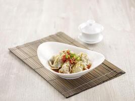 Pork Wanton in Chilli Vinaigrette with chopsticks served in a dish isolated on mat side view on grey background photo