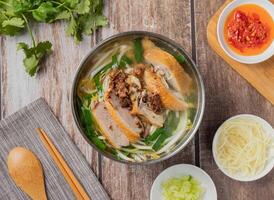 Duck meat rice noodles soup with chilli sauce, noodles, spoon and chopsticks served in dish isolated on napkin top view of hong kong food photo