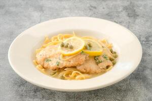 Specialty Chicken Piccata with lemon slice served in a dish isolated on background side view of fastfood photo