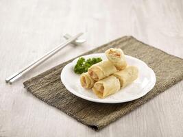 Crispy Vegetable Spring Roll Served in a dish isolated on wooden board side view on grey background photo