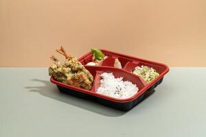 MIXED TEMPURA regular BENTO with sauce and chopsticks isolated on red background side view of japanese fast food photo