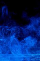 Abstract Blue Smoke Concept, Isolated on Dark Black Background with Wooden Table photo