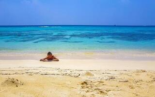 Man lying on beach sand and water on tropical beach Maldives. photo