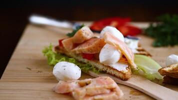 fried toast with salmon, cream cheese, salad, on a wooden table video