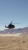 A helicopter flying over a desert with mountains in the background video