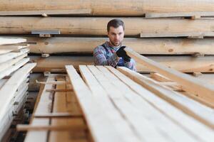 Timber harvesting for construction. Carpenter stacks boards. Industrial background. Authentic workflow. photo