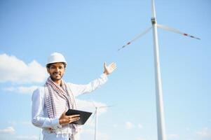 ingeniero India hombre trabajando a molino granja generando electricidad limpiar energía. viento turbina granja generador por alternativa verde energía. asiático ingeniero comprobación controlar eléctrico poder foto