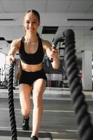 Woman training with battle ropes in gym photo