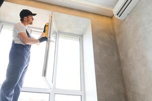 Construction worker repairing plastic window indoors, space for text. Banner design photo