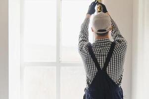 Worker in installing white plastic upvc window on house. photo