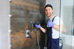 Professional handyman working in shower booth indoors photo