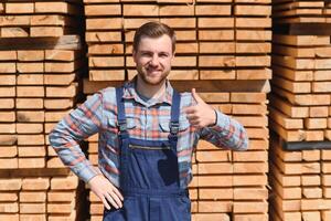 Carpenter in uniform check boards on sawmill photo