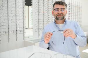 male customer choosing glasses in optics store photo