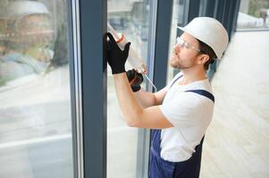 handsome young man installing bay window in new house construction site. photo