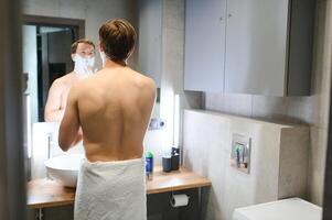 Confident guy using shaver in bathroom photo