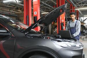 hombre coche técnico mecánico reparando coche problema de motor, durante sistema comprobación detalle, utilizando tableta computadora para mantenimiento y fijación en coche cochera. foto