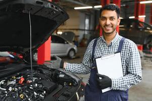 latin hispanic auto mechanic in uniform is examining a car while working in auto service photo
