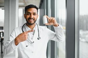 Handsome Indian Male Doctor holding empty white or blank dropper bottle photo