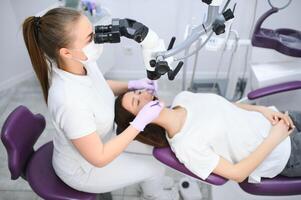 profesional dentista examen paciente con microscopio a el oficina foto