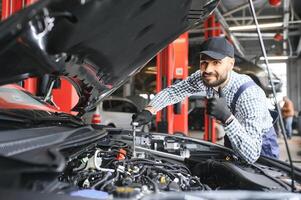 Mechanic examining under hood of car at the repair garage photo