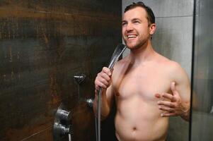 Young single handsome caucasian man are taking shower in the bathroom, he is singing, happy and relaxed. photo